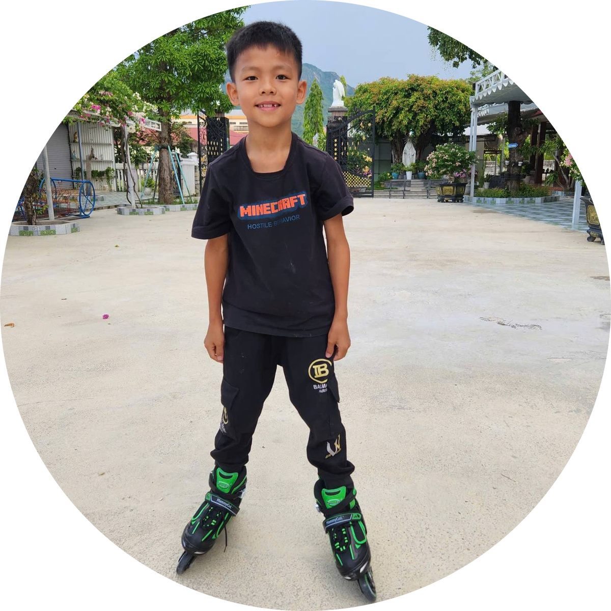 A smiling boy on inline skates in a courtyard.