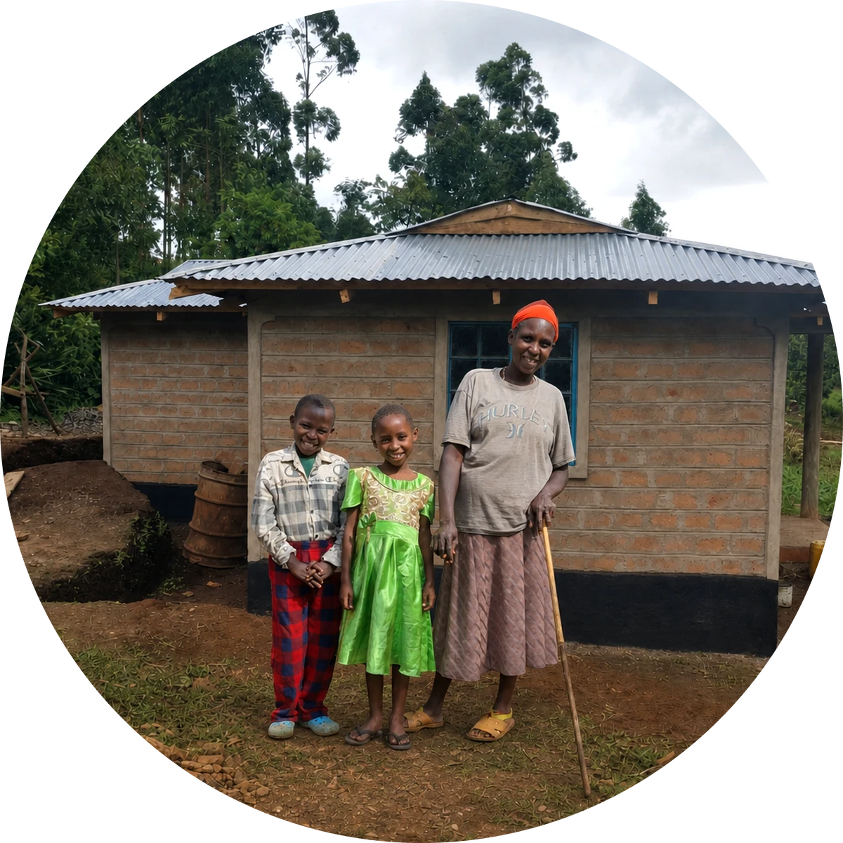 A grandmother and two smiling children stand in front of their new brick home.